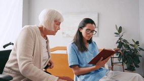 young brunette nurse reading book to elderly woman in nursing home