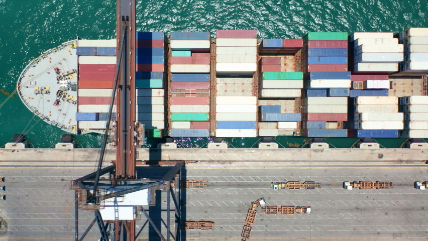 4K aerial view industrial crane unloading containers from vessel in port, water transportation business, international port Miami. Import and export logistics at industrial port. Global delivery cargo