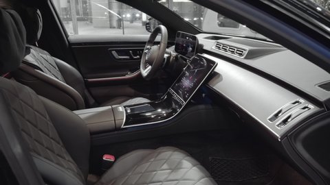 The driver's seat, front dashboard with new touchscreen displays and steering wheel in the interior of the newest Mercedes-Benz S-Class W223. Closeup cinematic 4k shot. Moscow, Russia - March, 2021.