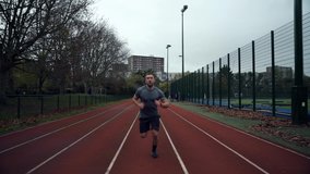 Caucasian male athlete running on tracking field checking watch