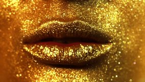 Fashion model golden makeup woman kiss lips in bright sparkles, golden lights, beautiful girl lips, mouth. Trendy glowing gold skin make-up. Art design make up. Glitter metallic shine makeup.  