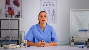 Authentic experienced woman nurse talking to camera and giving online medical consultation from private modern clinic. Remote healthcare service, video health conference, telemedicine, virtual meeting