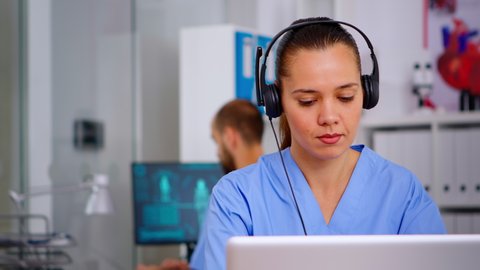 Doctor assistant using headphones in hospital answering to patients calls for appointments and consultations. Healthcare physician in medicine uniform, doctor nurse helping with telehealth