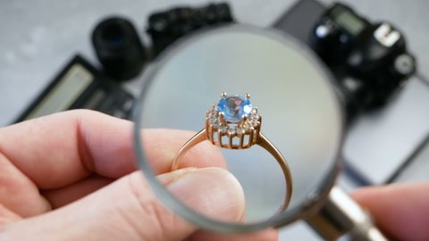 jeweler looking at ring with blue stone, jewerly inspect and verify, pawnshop concept