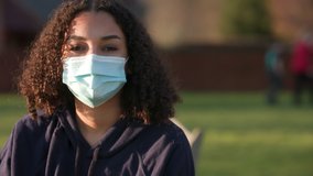 Beautiful mixed race African American girl biracial teenager young woman outside wearing and taking off a face mask during COVID-19 Coronavirus pandemic - Powered by Shutterstock - Get 15% off with code: PIKWIZARD15