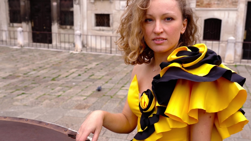 Lady with flounce on dress leans on old metal well cover