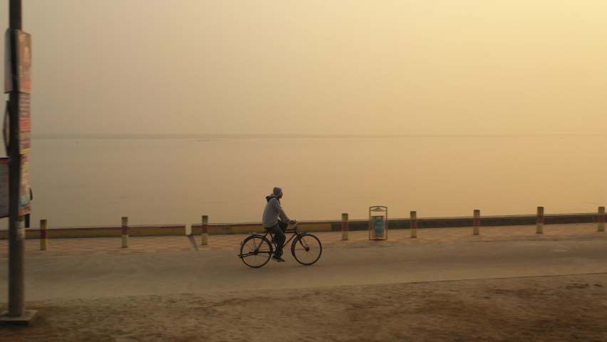 Low angle Drone shot of a man cycling at River side road.