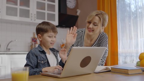Mom watches her little son playing online games on the computer. The young mother congratulates her son who won the game. Internet and computer addiction concept. 
