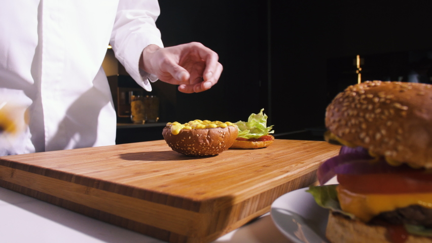 Chef Making Burger With Meat Cutlet, Cheese, Tomato, Onion In Fast Food Restaurant Kitchen. Cooking Delicious Hamburgers For Dinner In Cuisine. Person Prepare Meal In Kitchen. Fast Food Dish Close up. Royalty-Free Stock Footage #1068903290