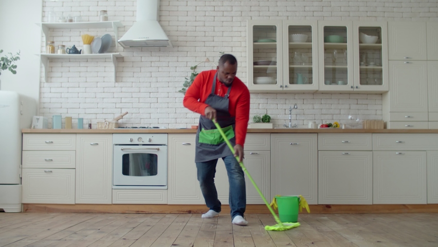 Optimistic black male dancing with mop during cleanup Royalty-Free Stock Footage #1068908183