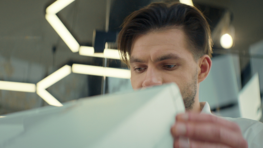Young Man In The Office. He Smiles. Handsome Man Standing Near The Photocopier.