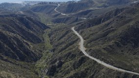 Aerial view drone flying above Malibu in Santa Monica Mountains. Drone 4K Video. Long road in the green mountains on California sunny day under blue sky