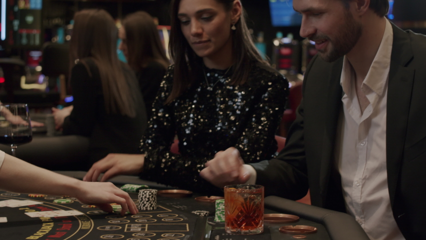 A young couple plays blackjack in an elite casino. The players are happy and waiting win. Gambling, nightlife