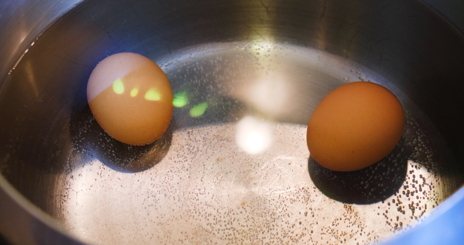 Placing eggs in water one by one using spoon. Boiling eggs preparation.