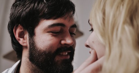 The bearded man touches the cheek of the blonde girl and looks into her eyes.
Concept of couple, relations, love,happiness.