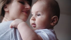 Close-up, mom at home holds a newborn baby in her arms, kissing him. Parenthood. Motherhood. Slow motion 4K video