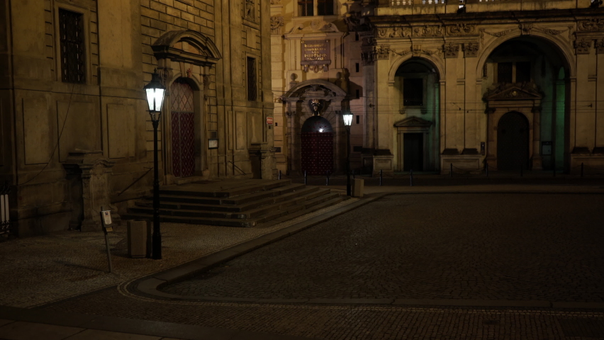 optical zoom lamp street light on the old pavement and in the background in a dark street a civilian and one police car drive at night in the old town of Prague Royalty-Free Stock Footage #1068919760