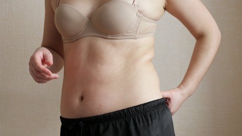 Unrecognizable woman touching fat on belly and sides.