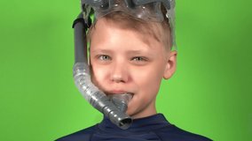 Closeup view 4k stock video portait of cute young white happy smiling kid wearing snorkeling goggles mask standing isolated on green background. Smiling and laughing emotional boy looks at camera