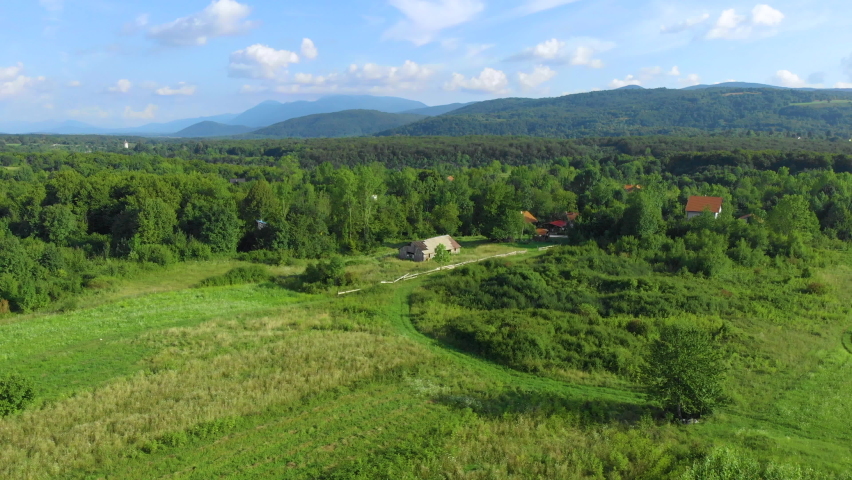 Drone. Aerial view. Summer. Sunny day. Abandoned old wooden farmhouse on a green meadow. Camera moves forward