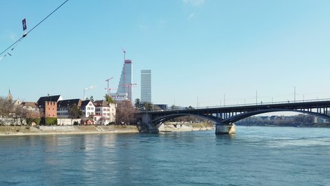 Basel city riverside skyline with traffic,constrution cranes and walking people,urban switzerland