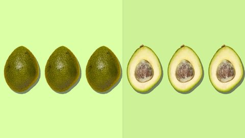 Stop motion animation Ripe whole green avocados move from left to right on a green background turning into cut avocado with a brown pit