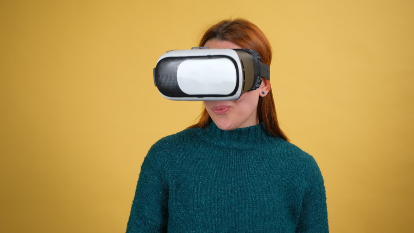 Amazed woman using VR app headset helmet to play simulation game, drawing. Watching virtual reality 3d 360 video. Isolated on yellow background in studio. Girl in VR goggles looking around Royalty-Free Stock Footage #1068929777