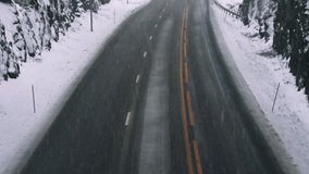 Snow falling on a highway with no traffic on a cold winters day. Asphalt with road salt keeping the road clear of ice and snow.