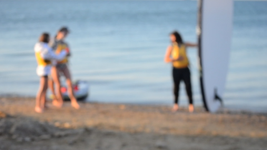 Blurred background. Many people standing on sea and take pictures with sup board