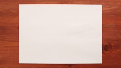 Crumpling white sheet of paper on wooden background - stop motion animation