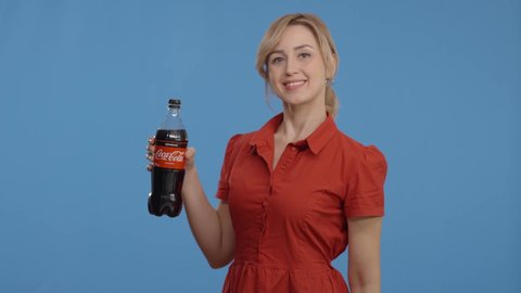Istanbul,Turkey-01.29.2021:Young woman drinking Coca Cola -Zero Sugar and being happy to cool off. Slow motion video.Indoor studio shot isolated on blue background.