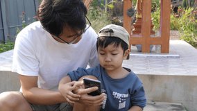 4K Authentic father and child watching video on smartphone outdoor vintage background. Dad and son have happy moment together. Concept of good relationship, technology connection, father's day.