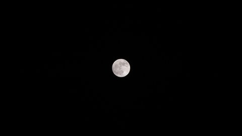 Bright full moon set against dark black sky at night