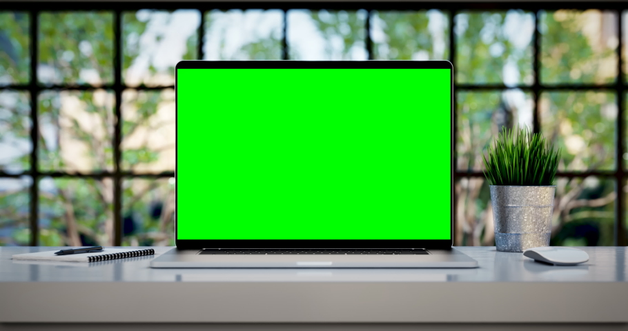 Laptop with blank green screen. Zoom in footage with trees swaying or moving in the wind. Home interior or loft office background, 4k 24fps UHD, loop video