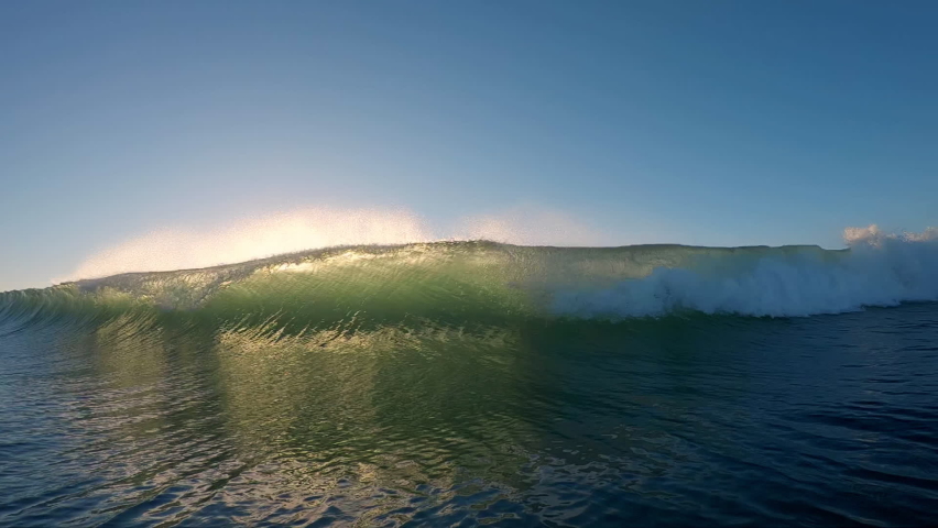 Ocean wave breaks at sunrise. Powerful ocean wave breaks on the camera during sunrise | Shutterstock HD Video #1068952802