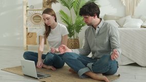 Healthy couple exercising at home, sitting on sport mat and watching videos on laptop