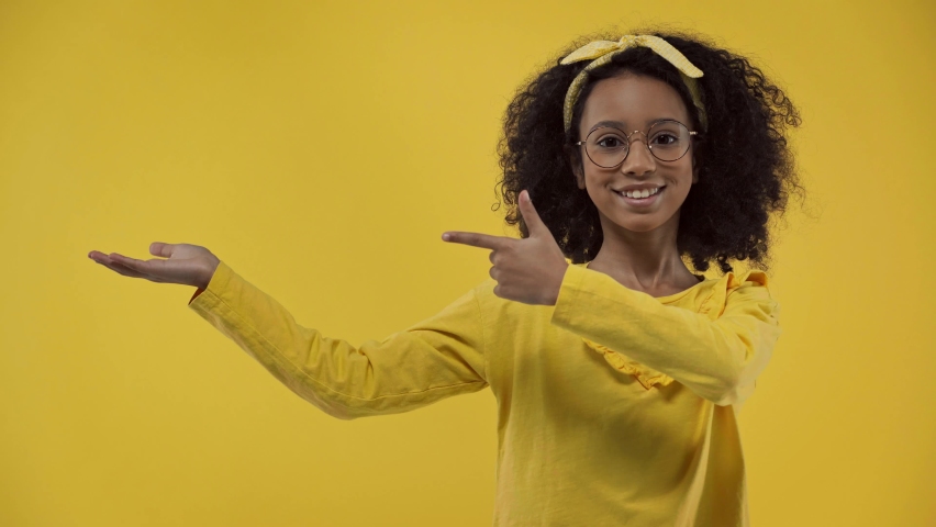 Cute african american kid pointing with finger isolated on yellow | Shutterstock HD Video #1068959306