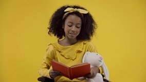 happy african american kid reading aloud isolated on yellow