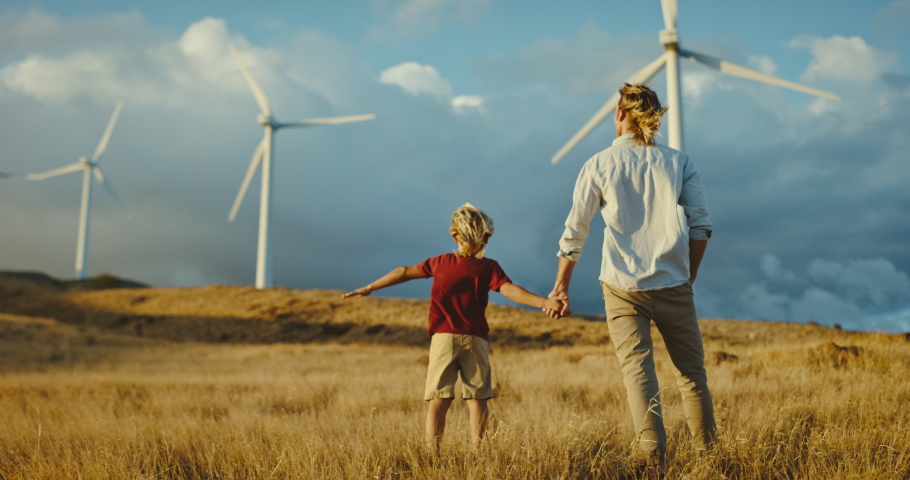Father and son with windmills on golden hillside at sunset, dreaming of a clean and sustainable future for generations to come, heart warming uplifting picture of clean energy for the environment