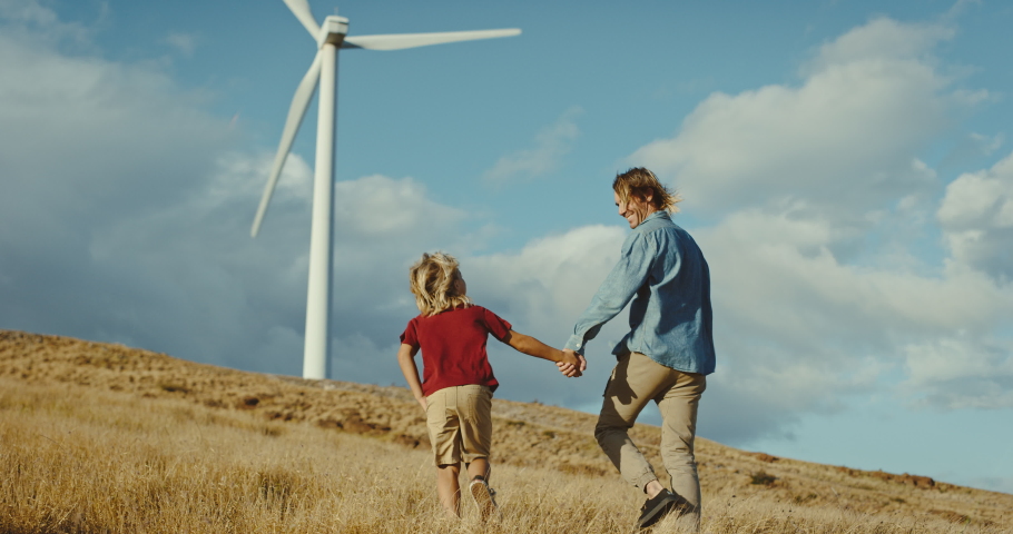 Happy father and son holding hands and walking under windmills, family lifestyle, spending quality time together, clean energy future, environment and sustainability concept | Shutterstock HD Video #1068963457