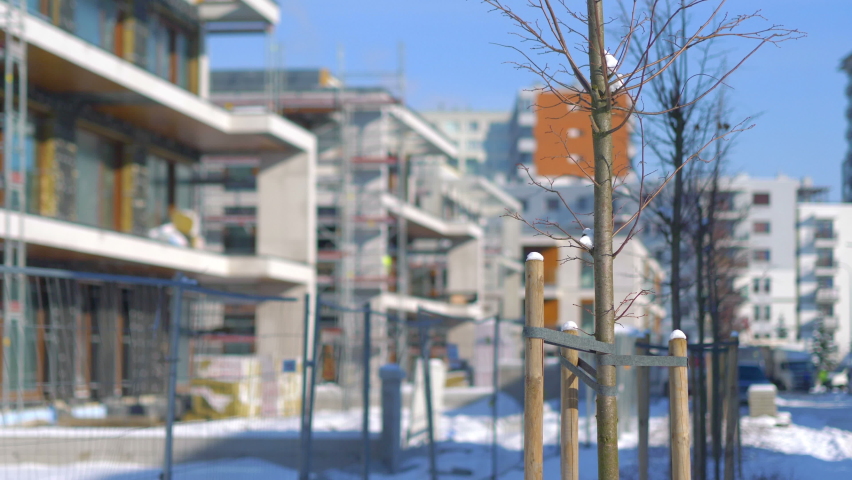 Young trees in front of the construction of a modern building in 4K Slow motion 60fps