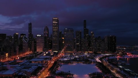 Urban Skyline of Chicago Loop at Night in Winter. New Eastside and Lake Michigan. Blue Hour. Aerial View. United States of America. Drone Flies Sideways and Upwards