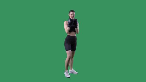 Female kick boxing fighter doing high kicks in slow motion. Full body on green screen chroma background. 
