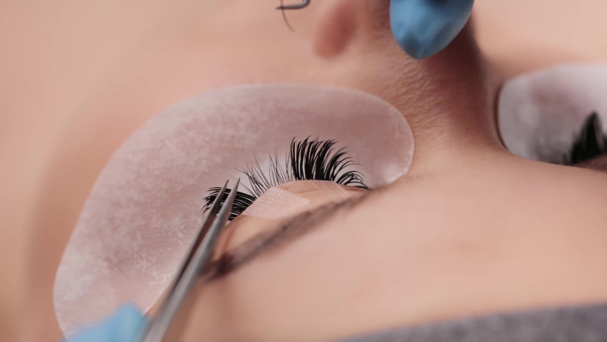 Eyelash extension procedure. The working process of professional beauty master lengthening female lashes. Fake eyelashes. Eyelashes extensions close up. Makeup artist and client in beauty salon. Royalty-Free Stock Footage #1068976522