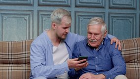 Happy bonding loving different male generations family resting together on comfortable sofa, using mobile applications, shopping in online store, watching funny video in social network, playing games