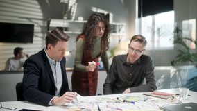 Team Of Architects Working On Project Paper Blueprint. Group Of Modern Business People In Casual Wear Discussing Architectural Designs While Sitting In The Creative Office. - Powered by Shutterstock - Get 15% off with code: PIKWIZARD15