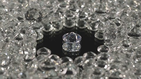 diamonds in different shape and different size place on center of circle on mirror are spinning around in black background.

