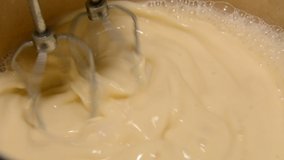 Household mixer whips milk mixture in kitchen utensils close-up
