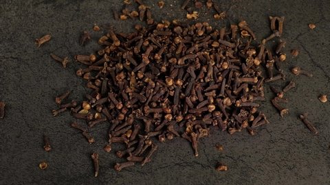 Many cloves are falling on a black background.
