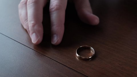 Fading feeling of love. Man takes off his wedding ring from his finger